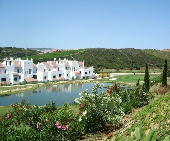 VIEW OF CALM SEA WITH BUILDINGS IN BACKGROUND