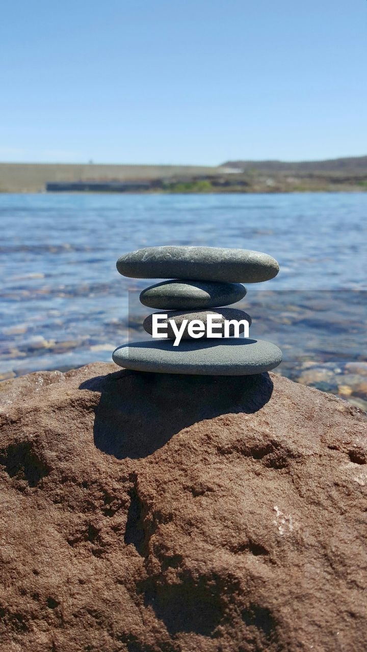 CLOSE-UP OF ROCK ON SEA SHORE AGAINST CLEAR SKY