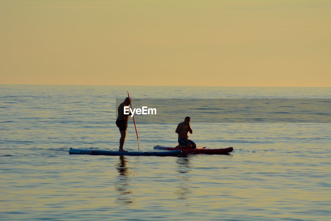 Men on paddleboards during sunset