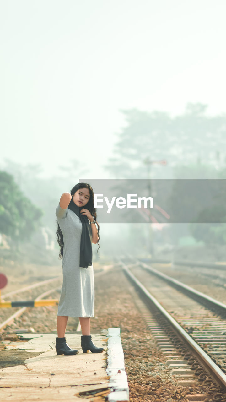 Full length of woman standing on railroad track against sky