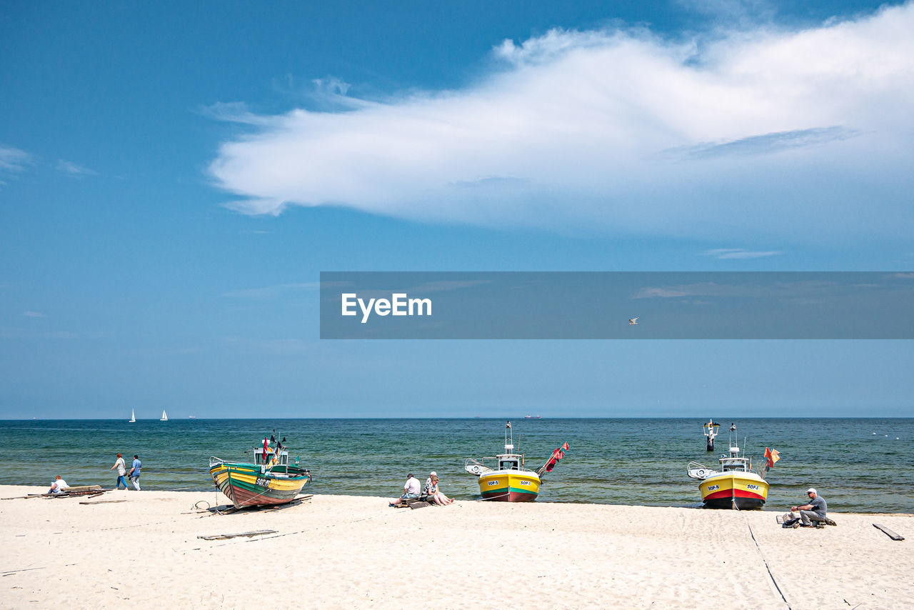 PEOPLE ON BEACH AGAINST SKY