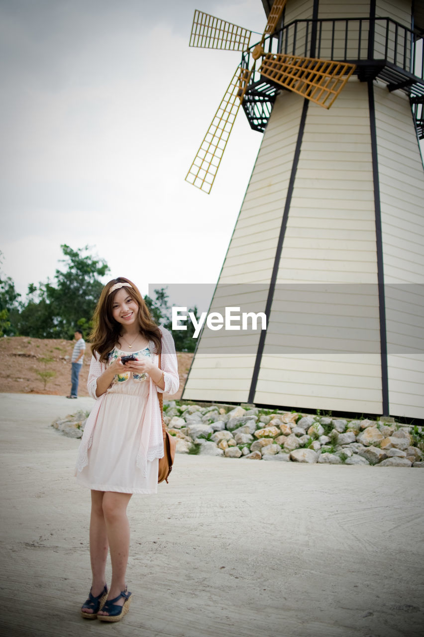 Portrait of smiling woman standing against traditional windmill