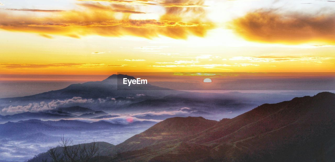 Scenic view of mountains with dramatic sky during sunset