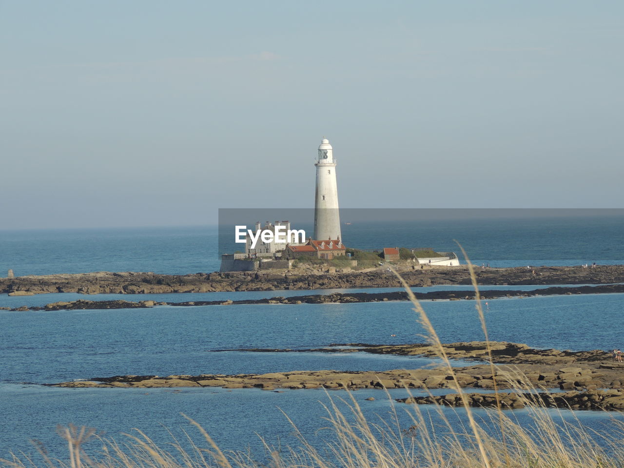 Lighthouse by sea against sky