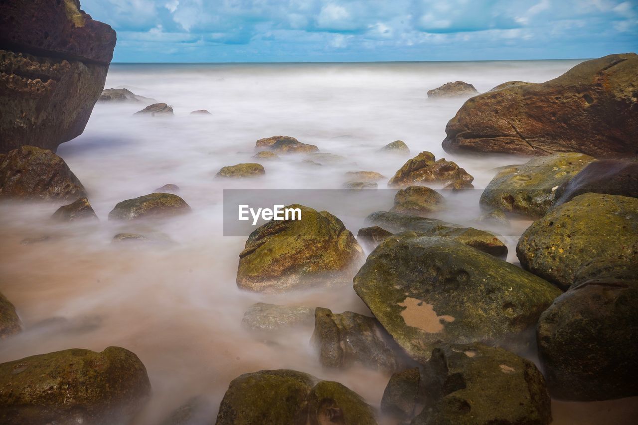 Scenic view of rocks on beach against sky