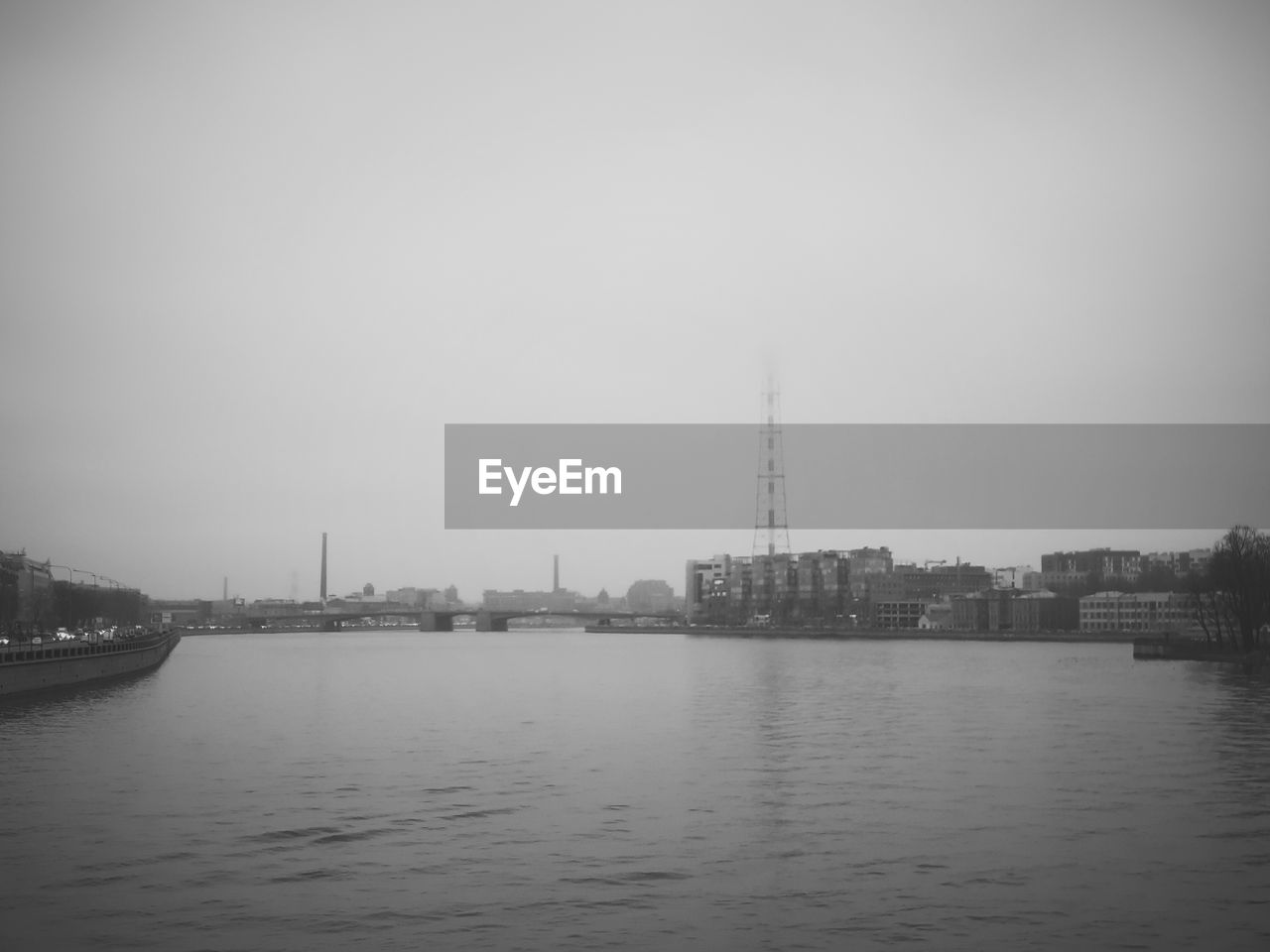 View of buildings by river against sky in city