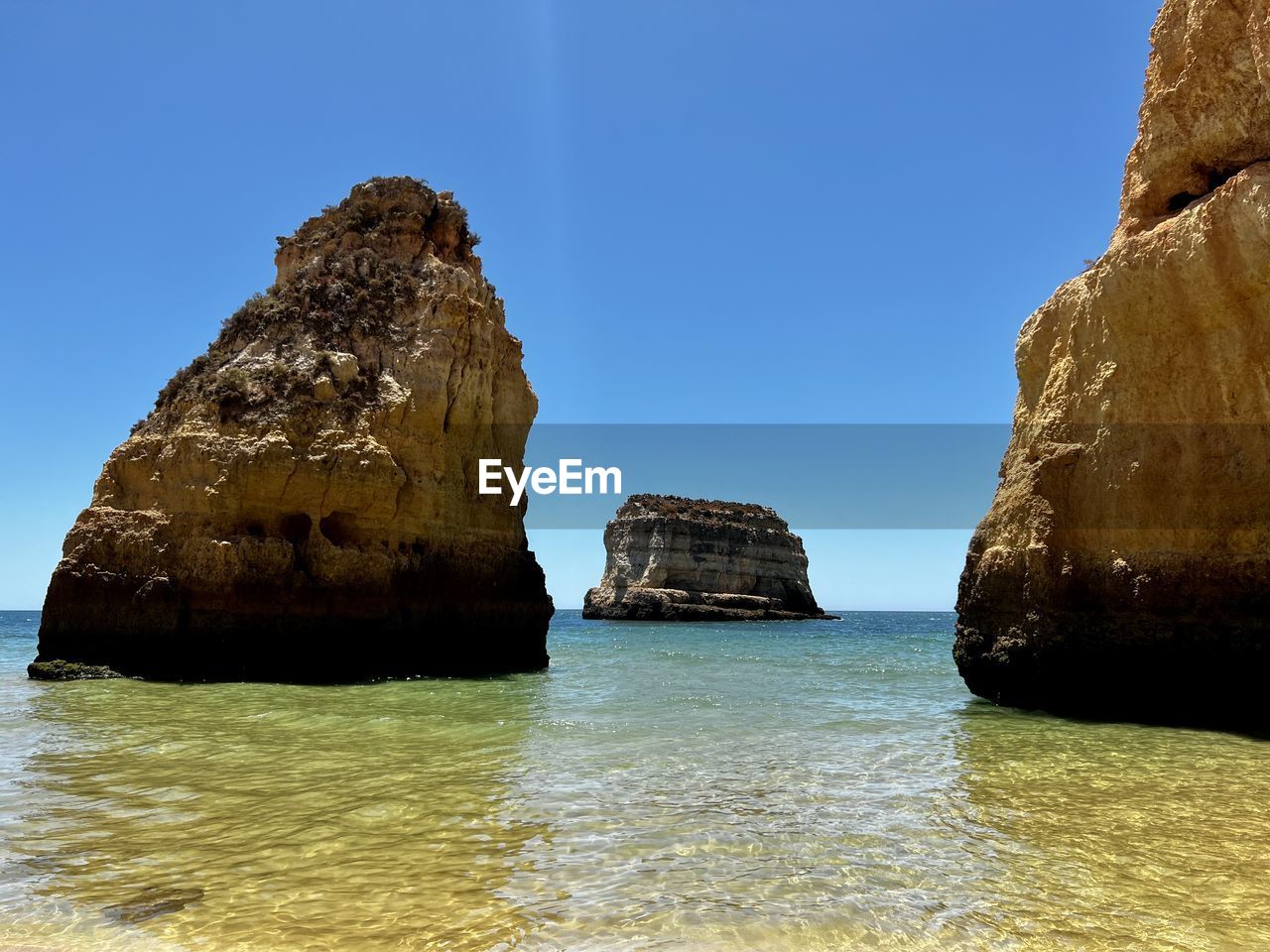 water, rock, sea, rock formation, beauty in nature, sky, scenics - nature, land, nature, coast, tranquility, beach, tranquil scene, blue, shore, formation, ocean, clear sky, cliff, no people, bay, idyllic, body of water, day, non-urban scene, stack rock, travel destinations, outdoors, geology, natural arch, travel, terrain, sunlight, islet, coastline, sunny, physical geography