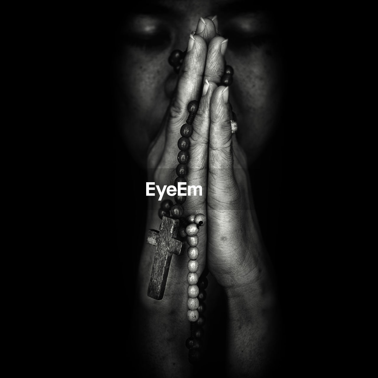 Close-up of woman praying with rosary in darkroom