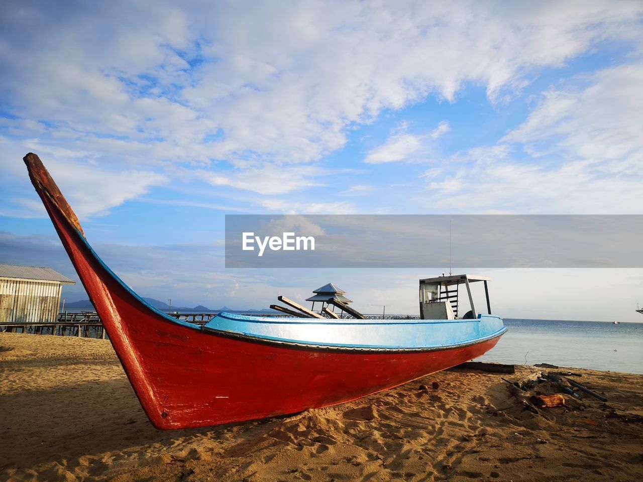 FISHING BOAT MOORED ON BEACH AGAINST SKY
