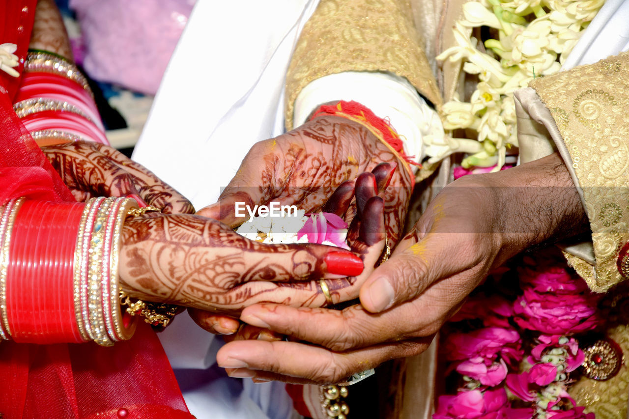 An indian bride and groom's hand being tied together before the wedding rituals