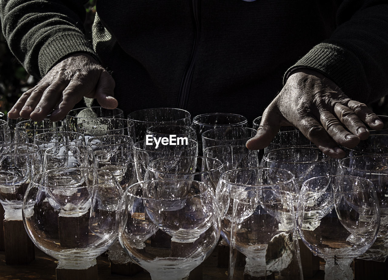 Midsection of man touching wineglasses