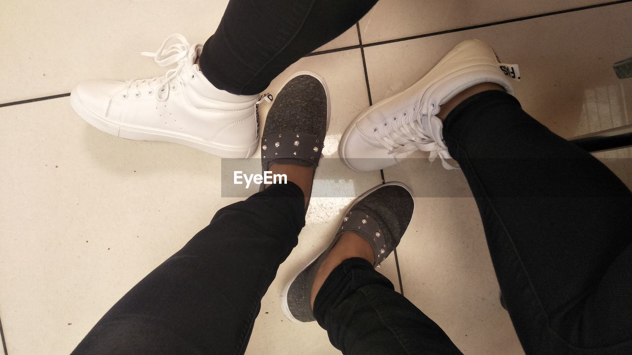 black, shoe, low section, human leg, white, footwear, limb, human limb, lifestyles, adult, high angle view, personal perspective, clothing, one person, indoors, leisure activity, men, women, human foot, standing, arm, flooring, person, casual clothing, walking shoe