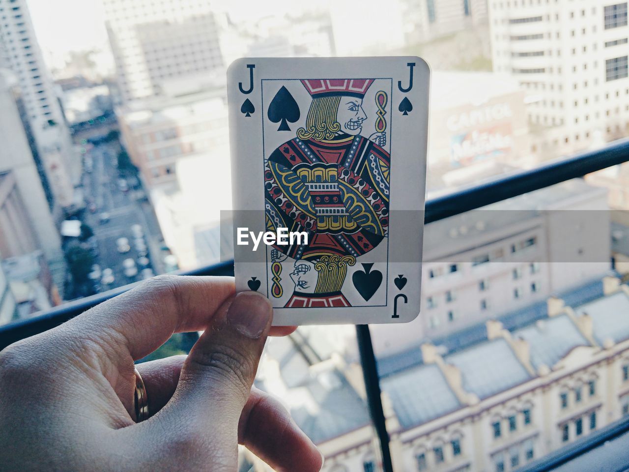 Cropped hand of person holding playing card on balcony in city