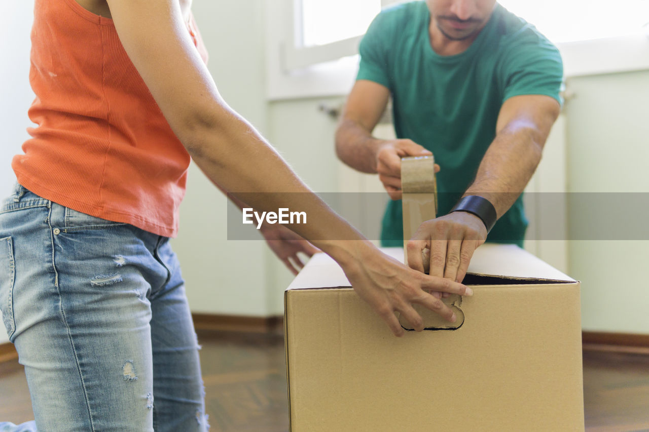 Couple packing cardboard box, partial view