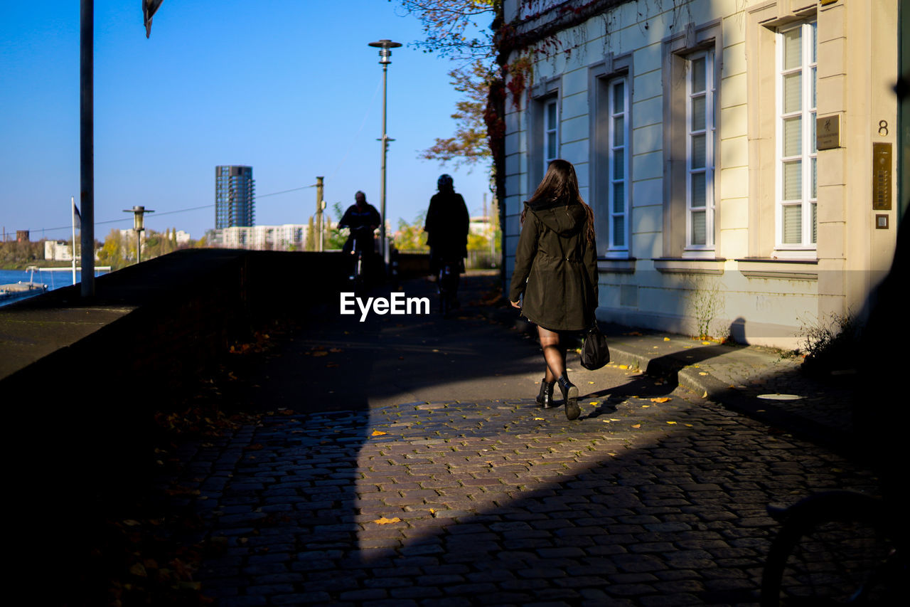 Rear view of woman walking on footpath in light framing 