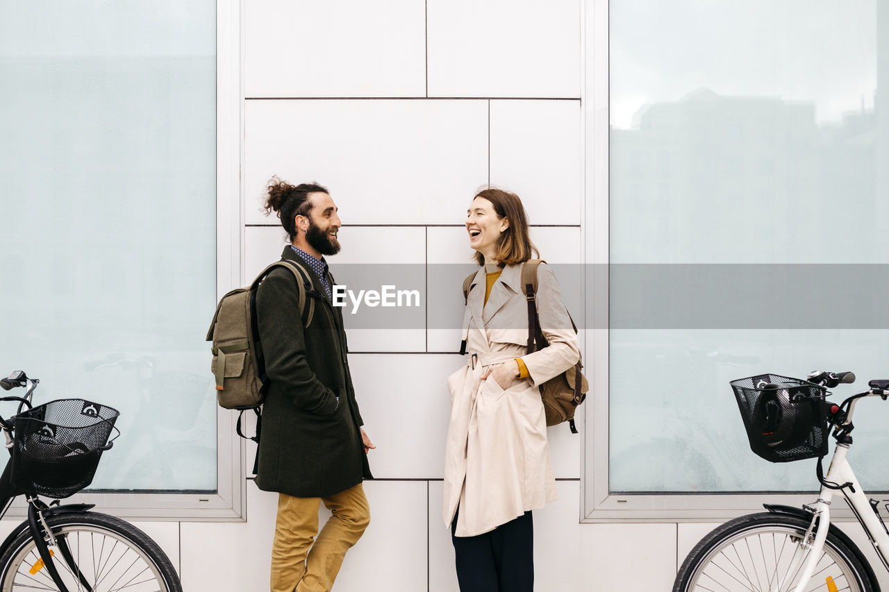 Man and woman with e-bikes standing at a building talking