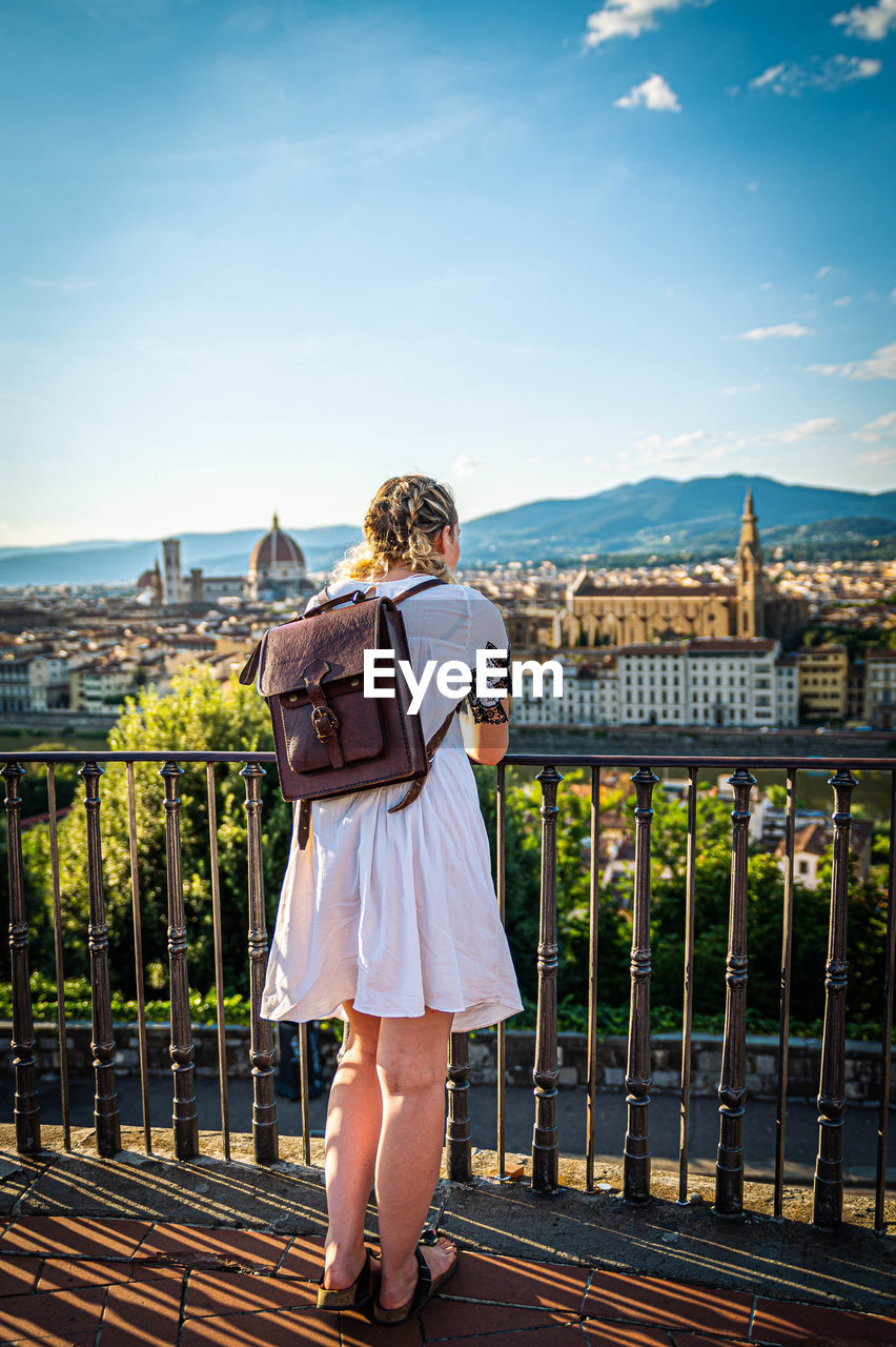 Rear view of woman standing by railing against sky