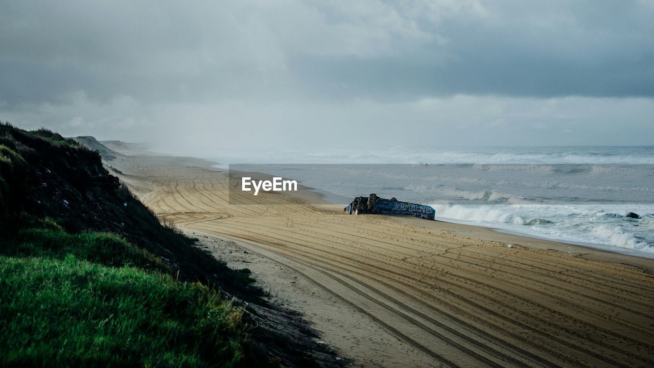 Scenic view of beach against cloudy sky