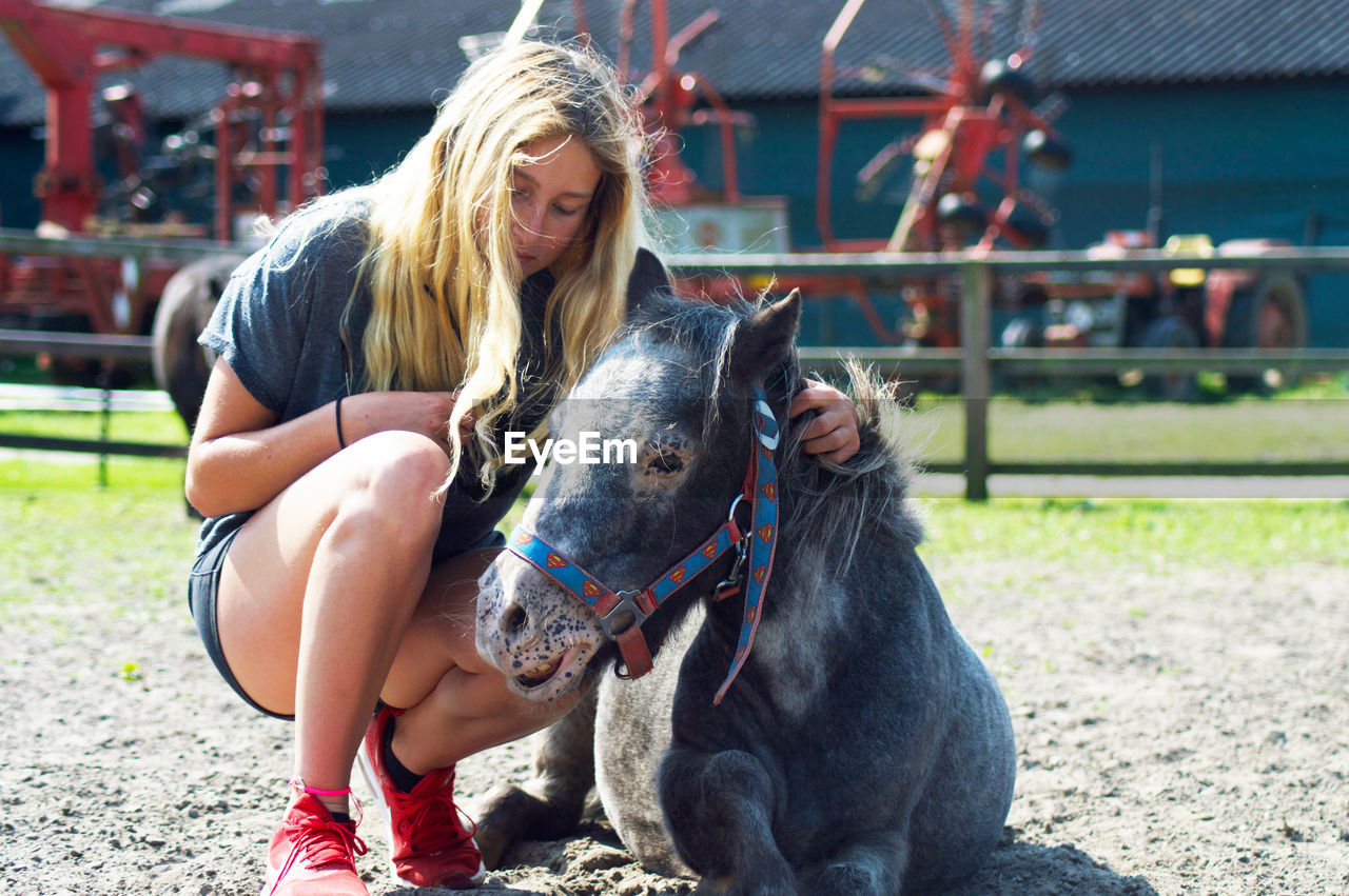 Rear view of woman petting pony