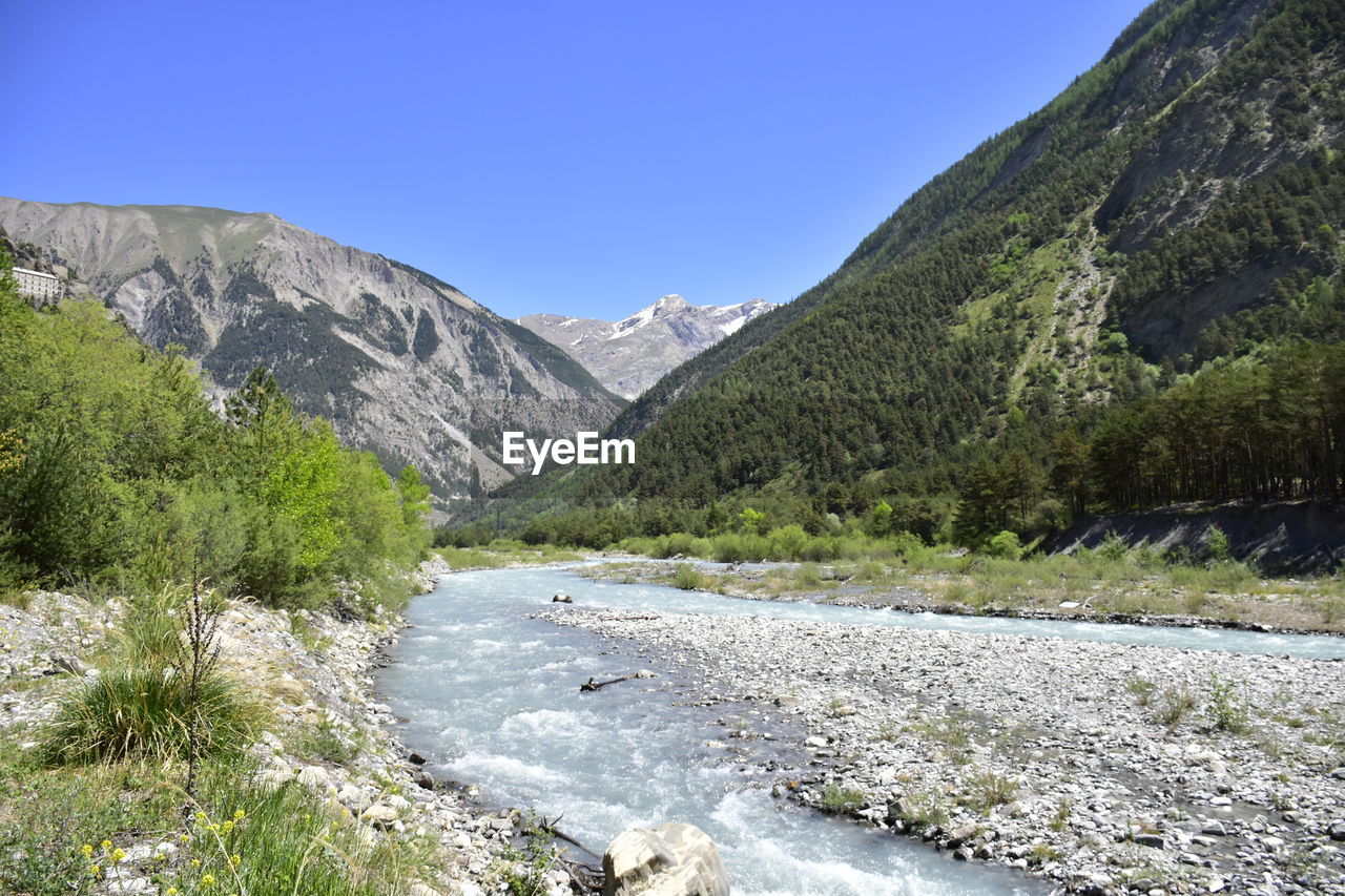 Scenic view of river amidst mountains against clear sky