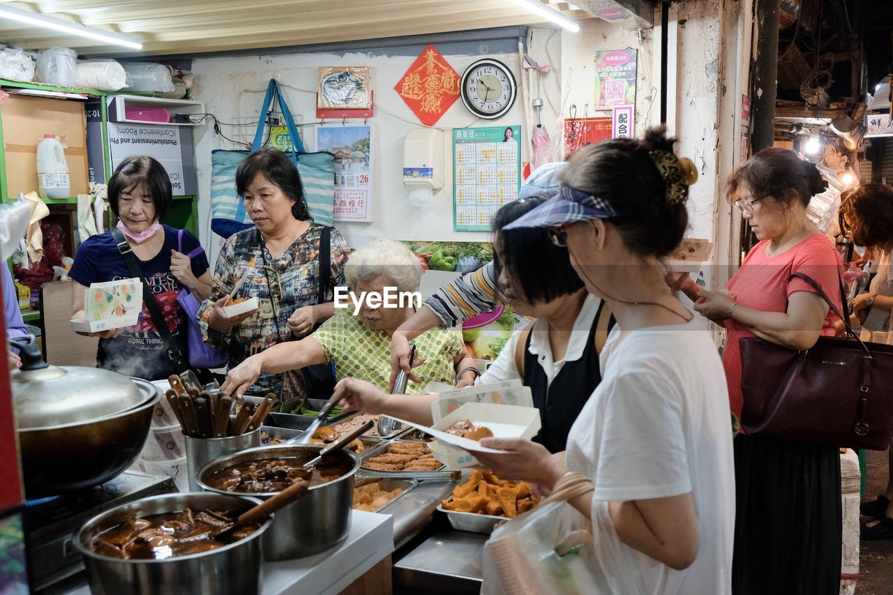 GROUP OF PEOPLE IN RESTAURANT AT MARKET STALL