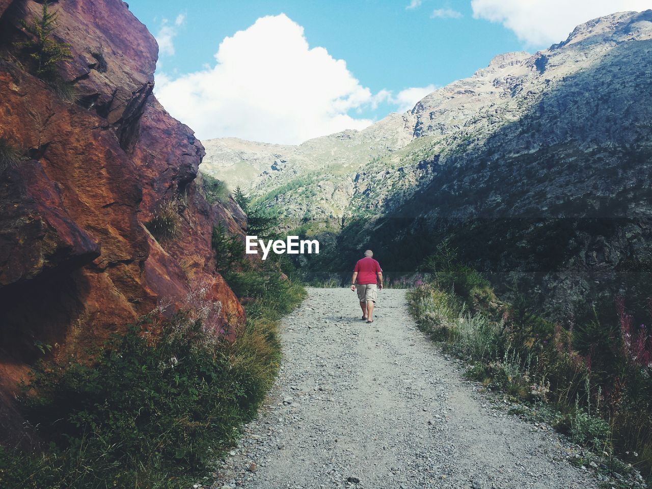 Rear view of man walking on dirt road