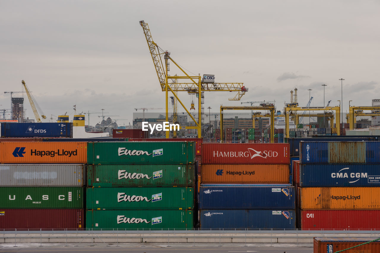 Stack of cargo containers at harbor against sky