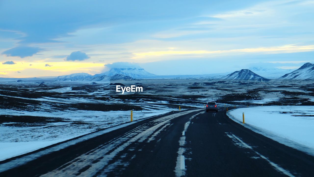 Road passing through mountains during sunset