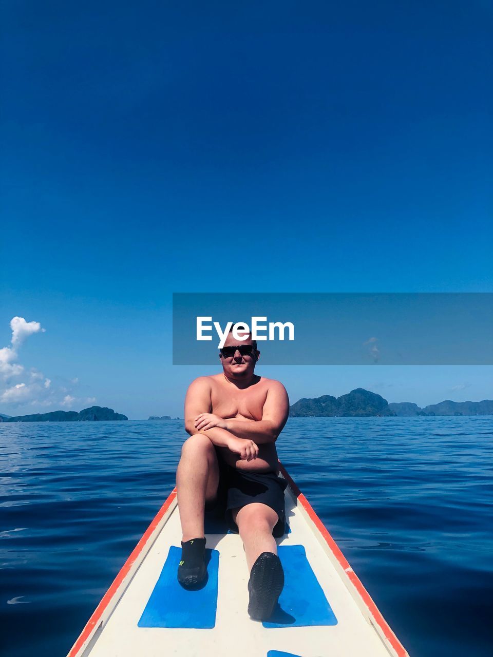 SHIRTLESS MAN IN SEA AGAINST BLUE SKY