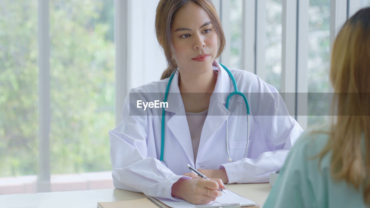 Young asia doctor consult female patient and checkup in hospital , healtcare and assistance concept