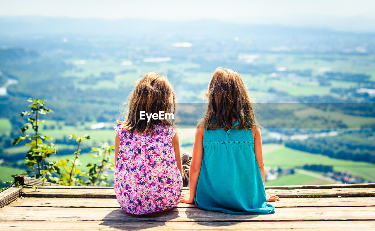 Sisters sitting against landscape