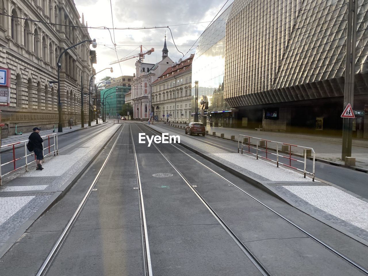 architecture, transport, transportation, built structure, city, building exterior, railroad track, track, rail transportation, lane, train station, metropolitan area, mode of transportation, public transport, travel, city life, sky, street, public transportation, railroad station, travel destinations, day, road, cloud, vehicle, group of people, nature, outdoors, building, infrastructure, urban area, the way forward, city street, diminishing perspective, men, adult, sign