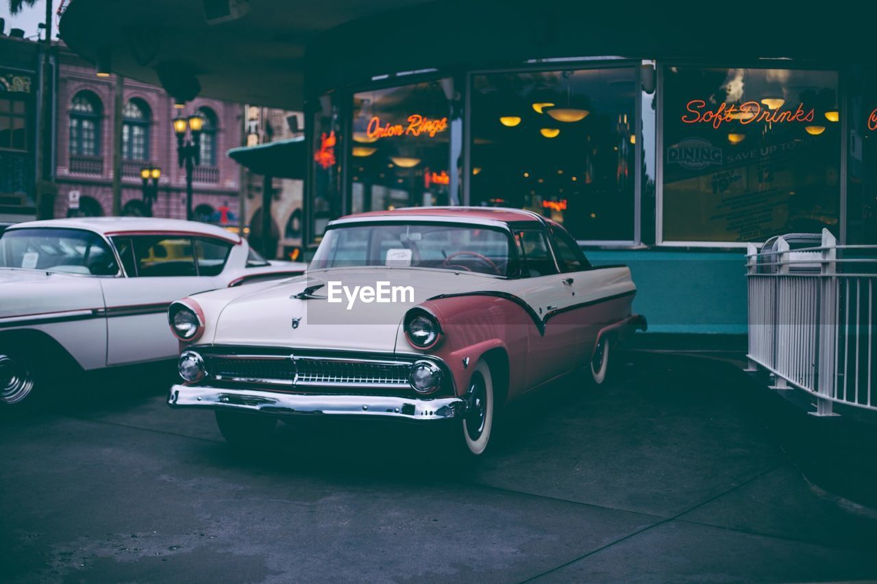 Vintage cars parked against building in city at dusk