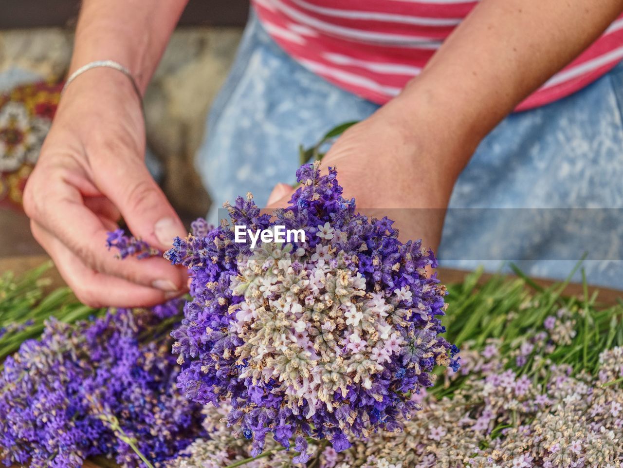 Girl hands with scissors and string preparing lavender flowers bunches on wooden table.