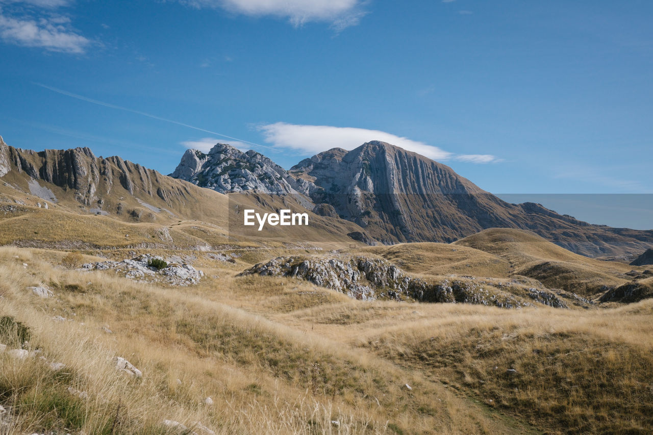 Scenic view of landscape and mountains against blue sky