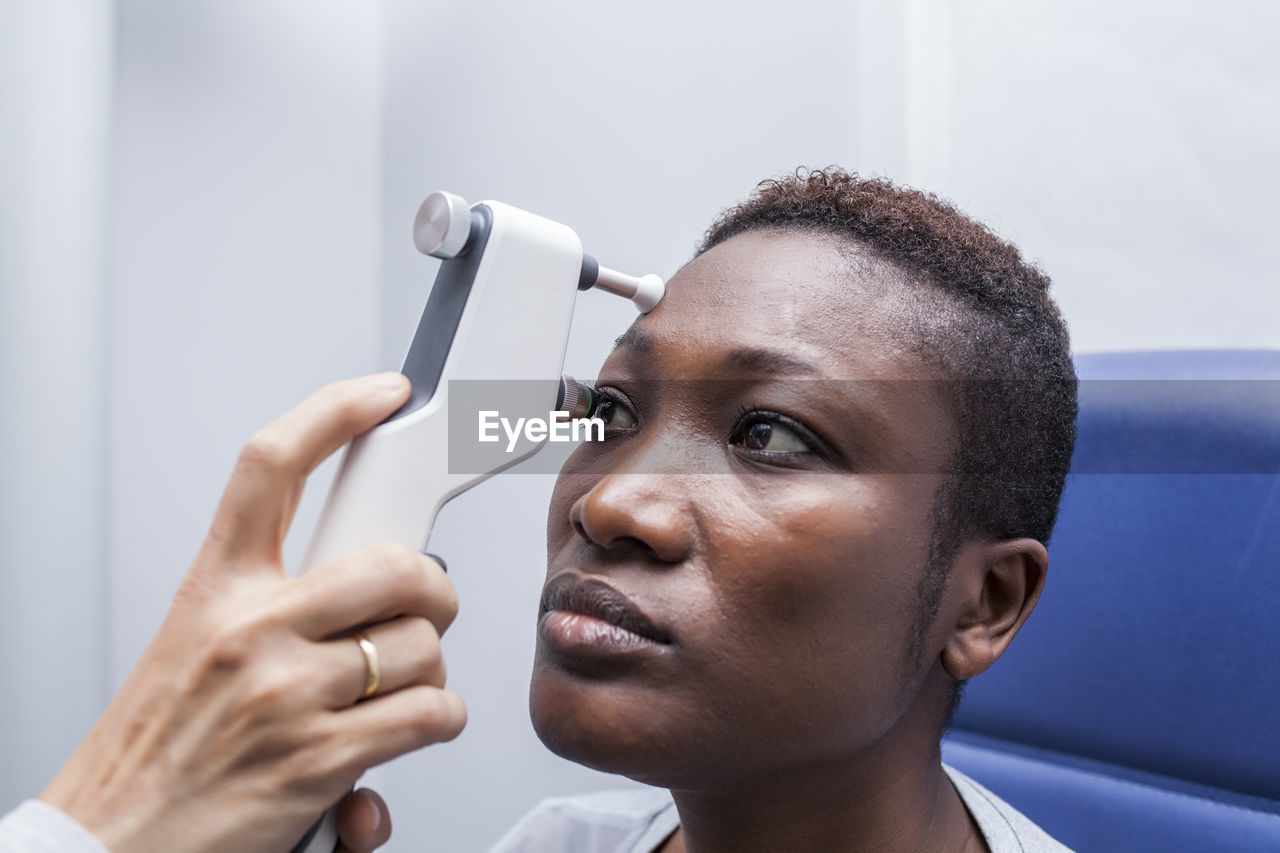 Optometrist using an ophthalmoscope during study of the eyesight of a black woman