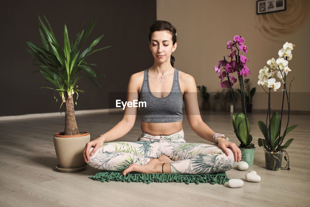 Woman doing meditation at yoga studio in the middle of flowers