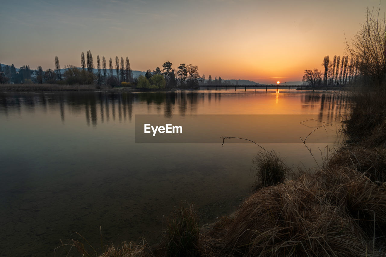 Scenic view of lake against sky at sunset