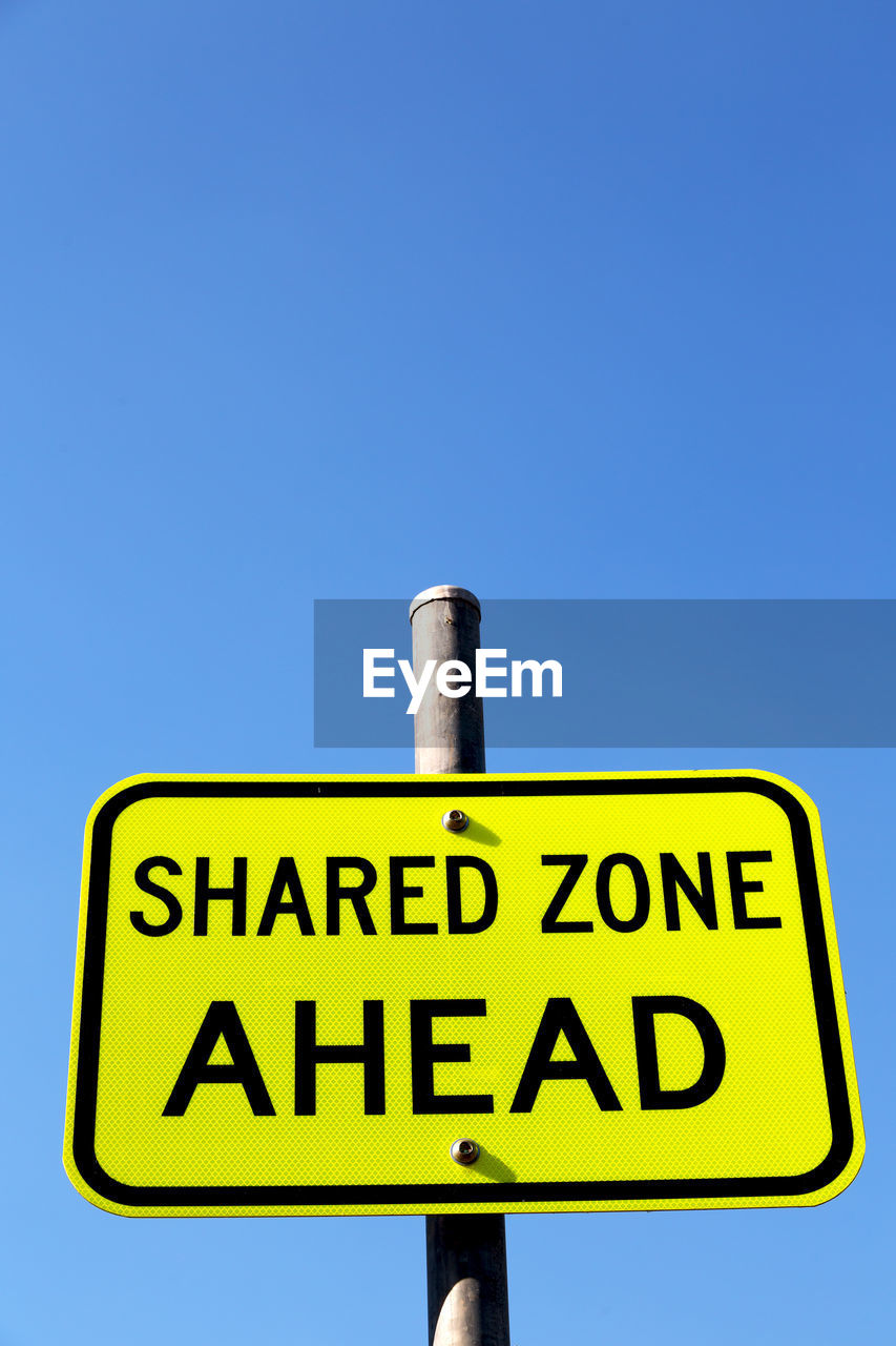 LOW ANGLE VIEW OF INFORMATION SIGN AGAINST BLUE SKY