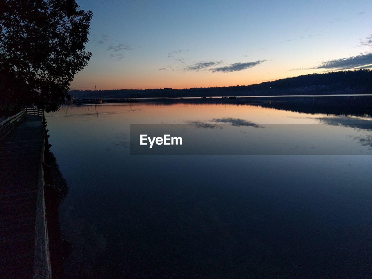 REFLECTION OF TREES IN LAKE AGAINST SKY