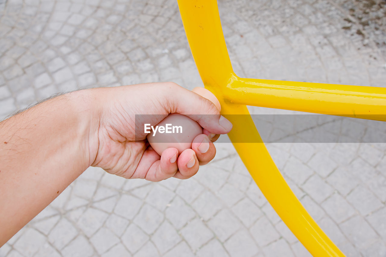 CLOSE-UP OF PERSON HAND HOLDING YELLOW RING