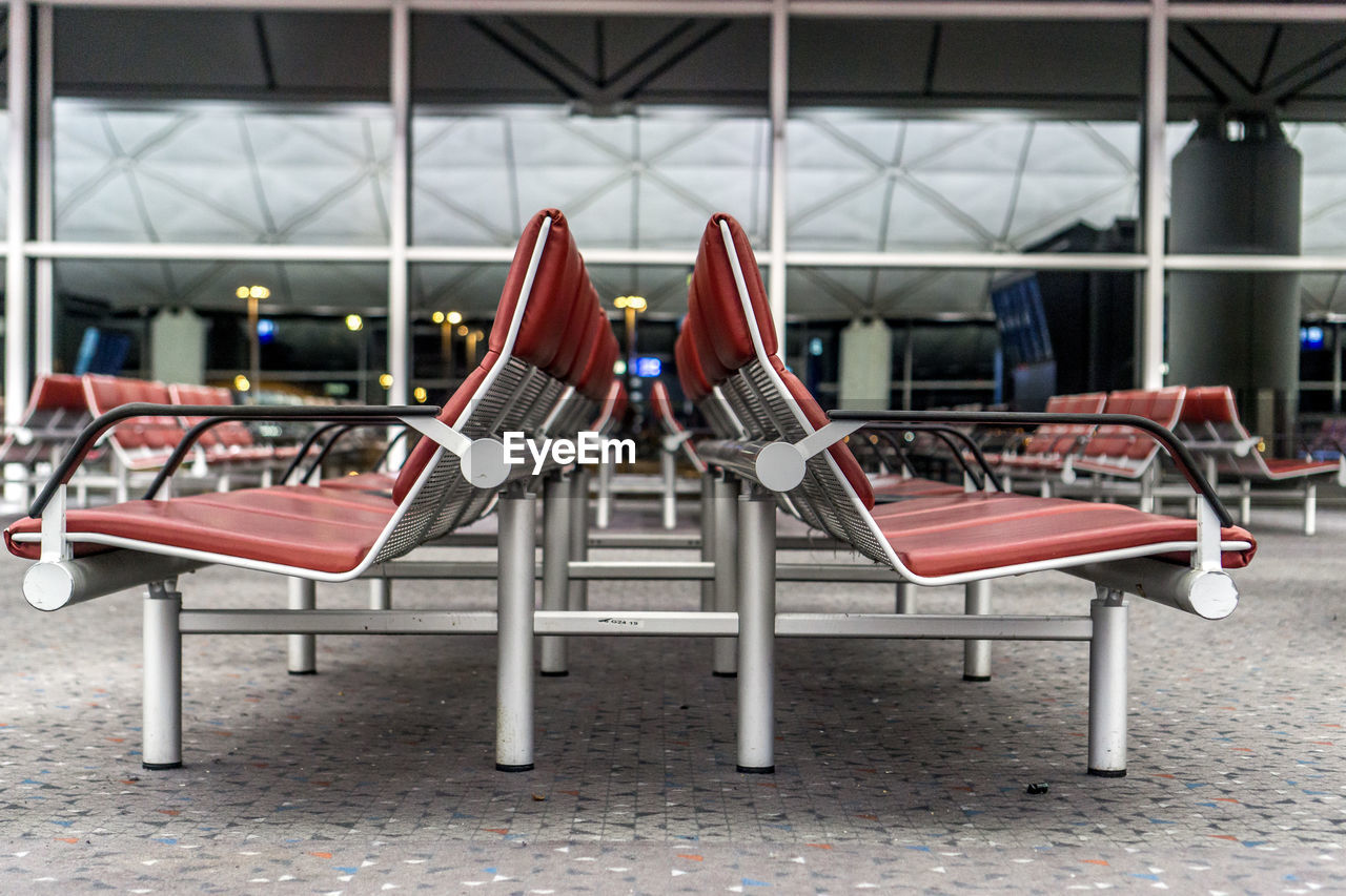 EMPTY CHAIRS AND TABLES AT AIRPORT AGAINST SKY