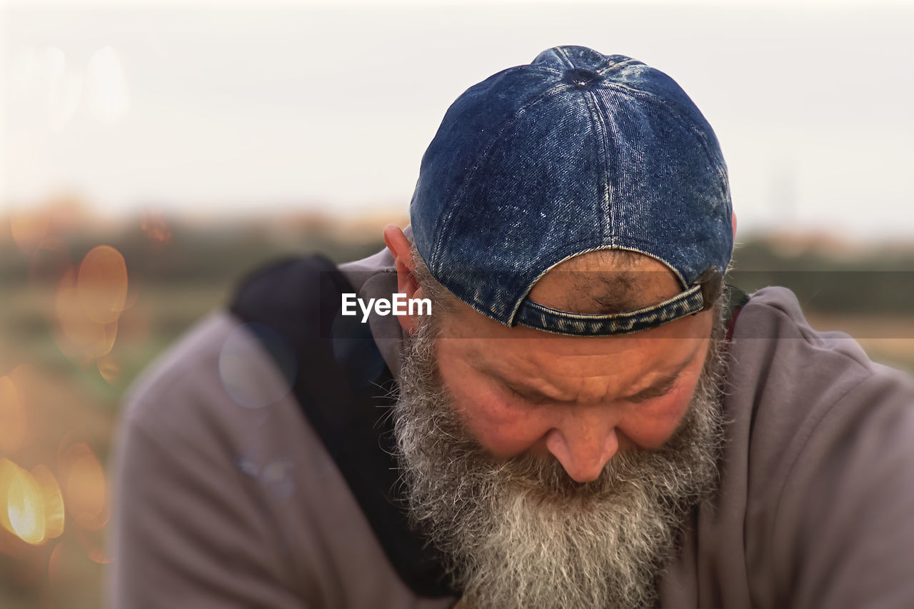 beard, facial hair, adult, men, one person, portrait, headshot, clothing, human hair, person, lifestyles, sky, nature, hat, front view, close-up, casual clothing, hipster, focus on foreground, outdoors, mature adult, fashion, glasses, looking, knit hat, leisure activity, day, emotion, cap, copy space, serious