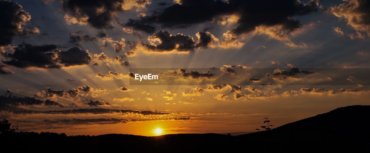 SCENIC VIEW OF DRAMATIC SKY OVER SILHOUETTE MOUNTAINS DURING SUNSET