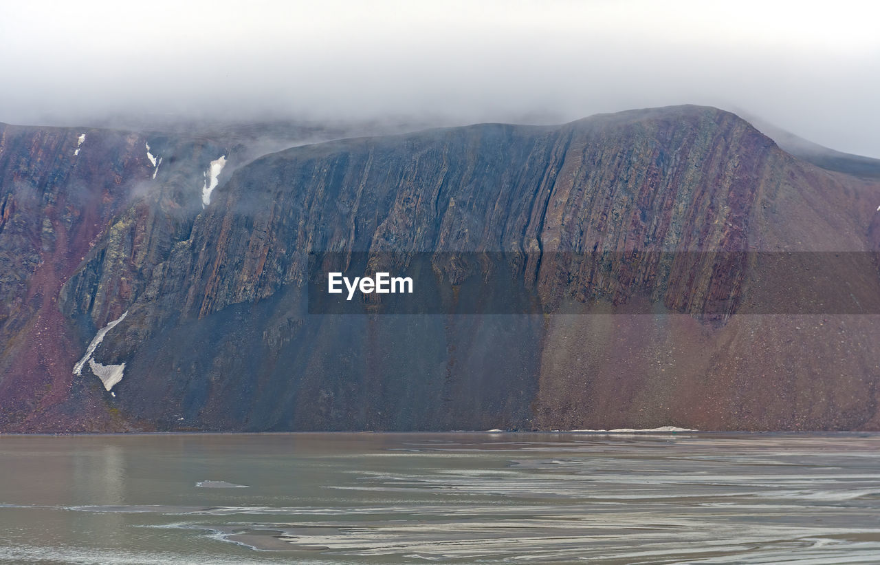 environment, mountain, landscape, water, scenics - nature, land, beauty in nature, nature, no people, travel destinations, non-urban scene, travel, outdoors, sky, cold temperature, lake, geology, fog, day, tranquility, tranquil scene, mountain range, winter, tourism, ice, rock