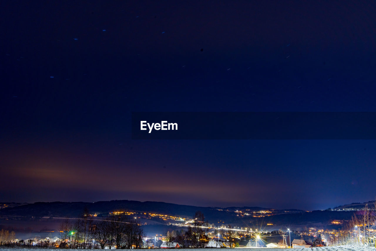 Aerial view of illuminated cityscape against sky at night