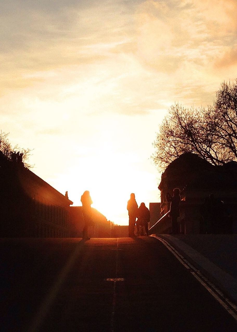 Silhouette people walking on road at sunset