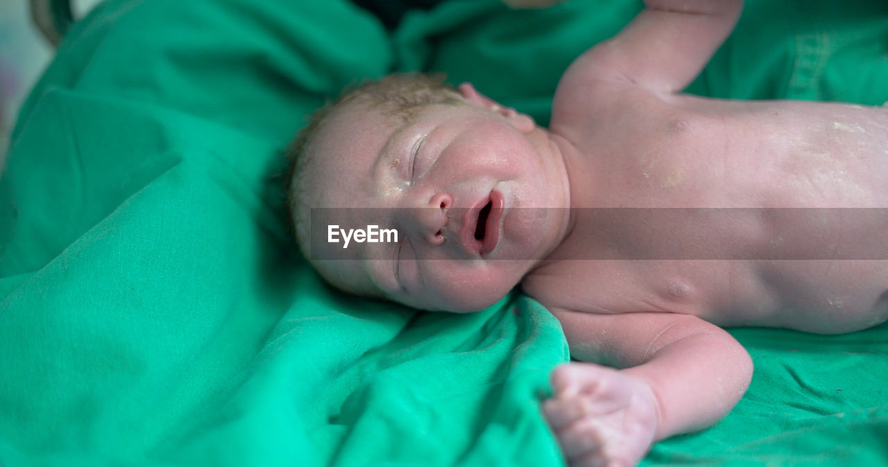 Close-up of baby boy lying on bed