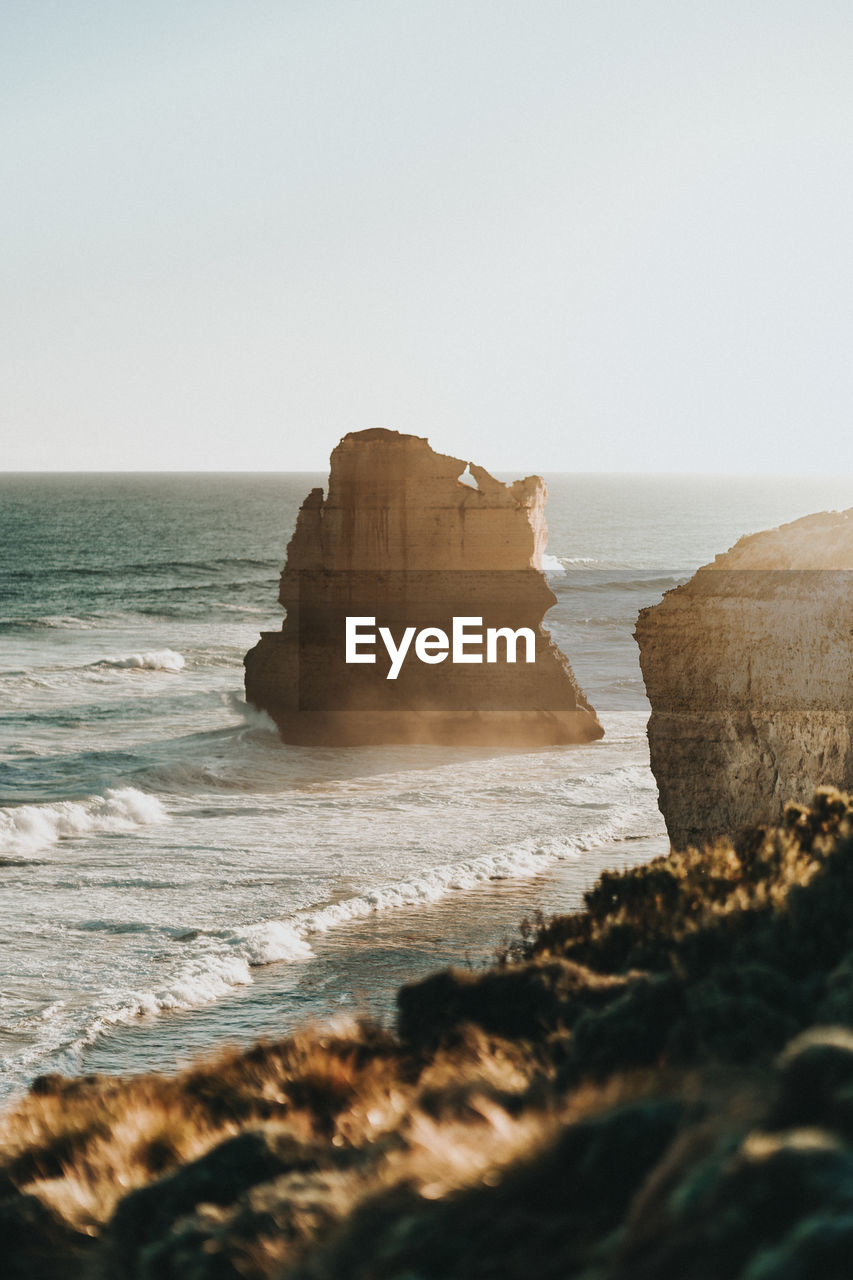 Scenic view of rocks in sea against clear sky