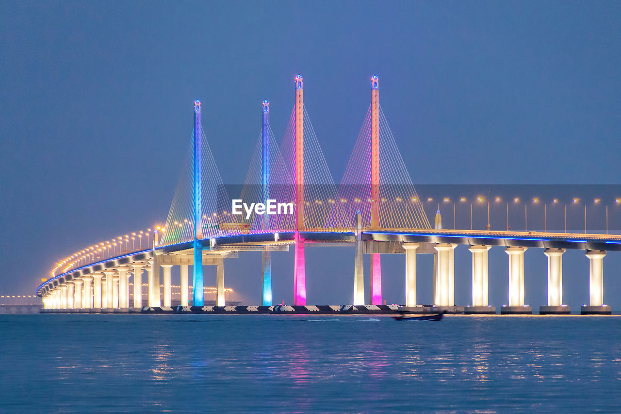 Illuminated colorful penang bridge over strait of malacca against clear sky at dusk